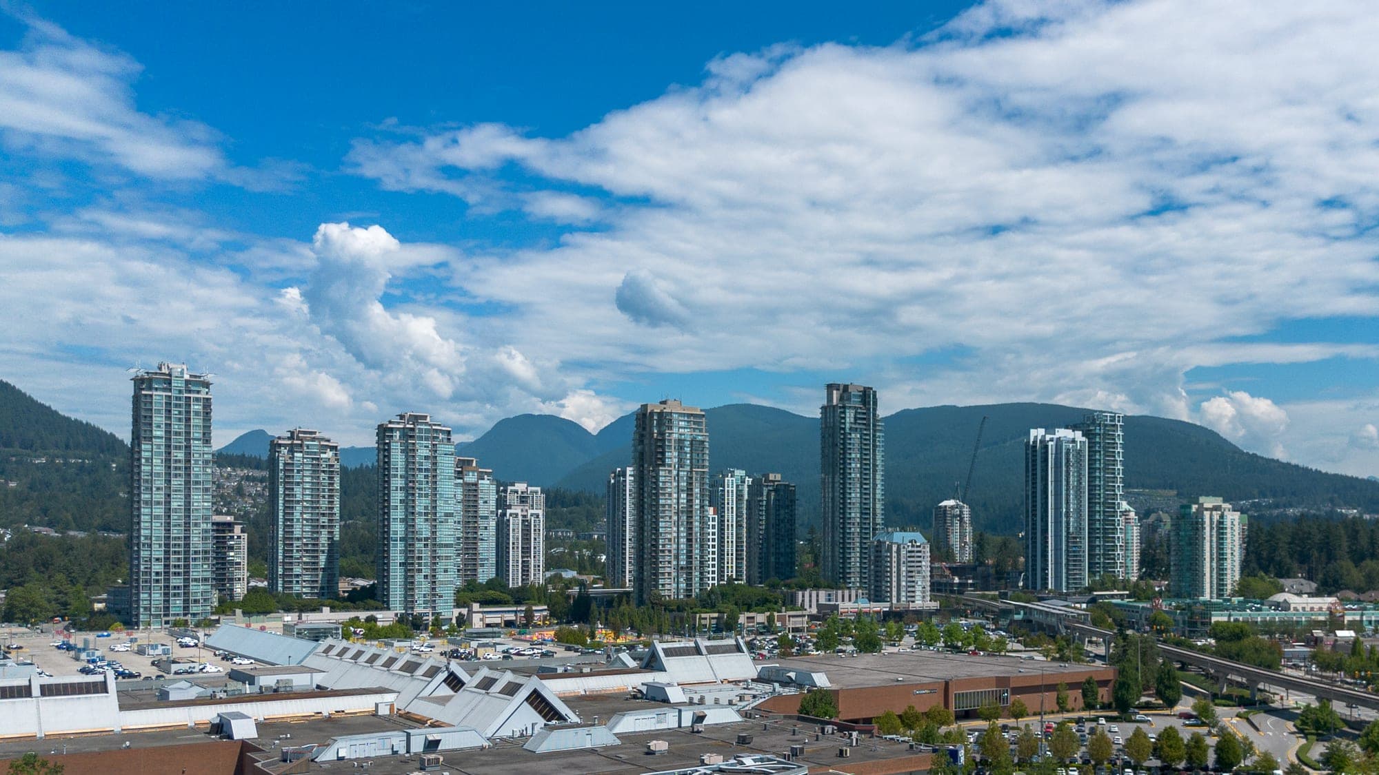 Coquitlam Town Centre skyline with new residential high-rise towers around the Lafarge Lake–Douglas SkyTrain station and Coquitlam's Coast Mountains in the background.