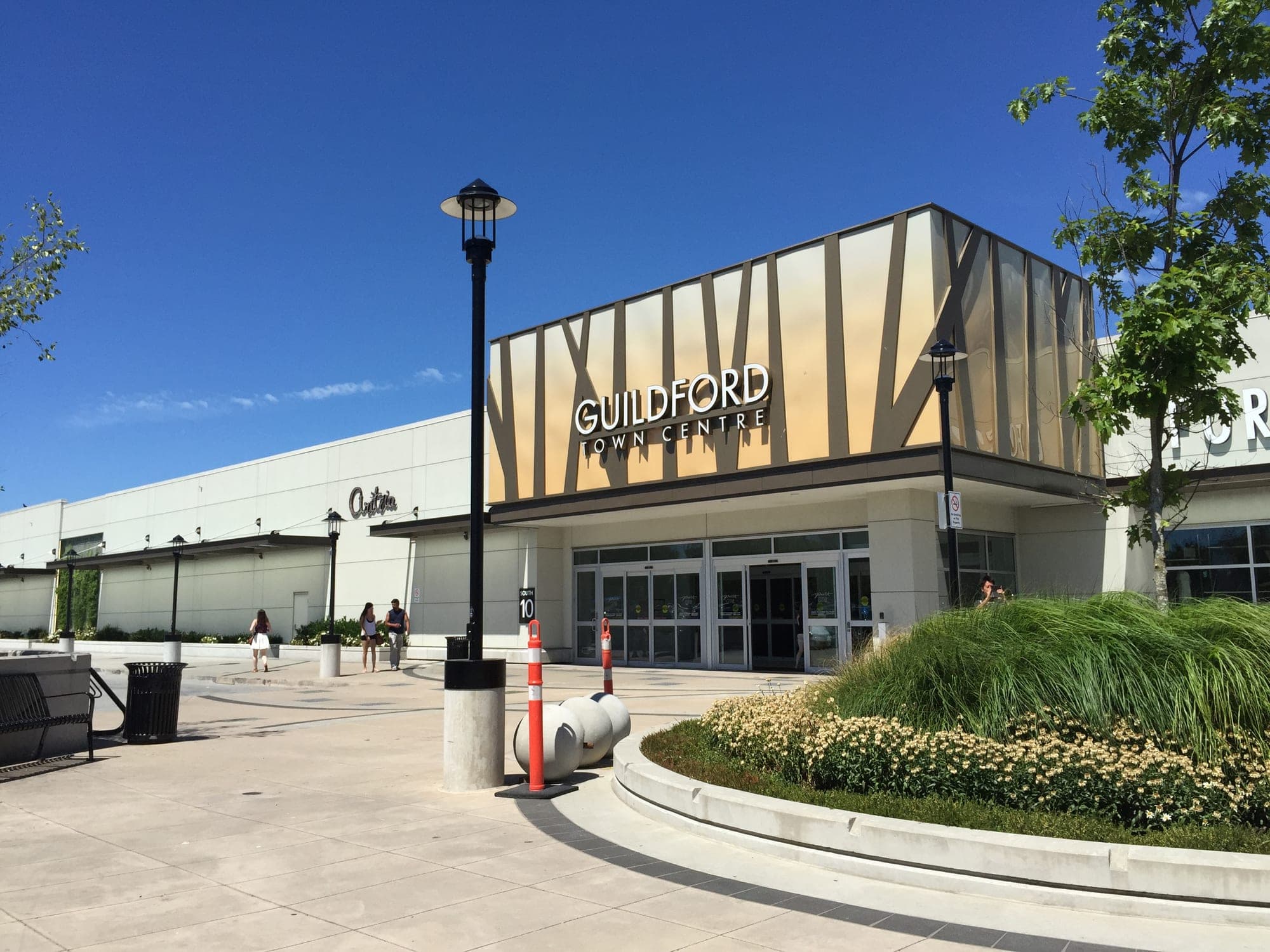 The exterior of Guildford Town Centre shopping mall in Surrey, with its glass atrium entrance and main parking lot.