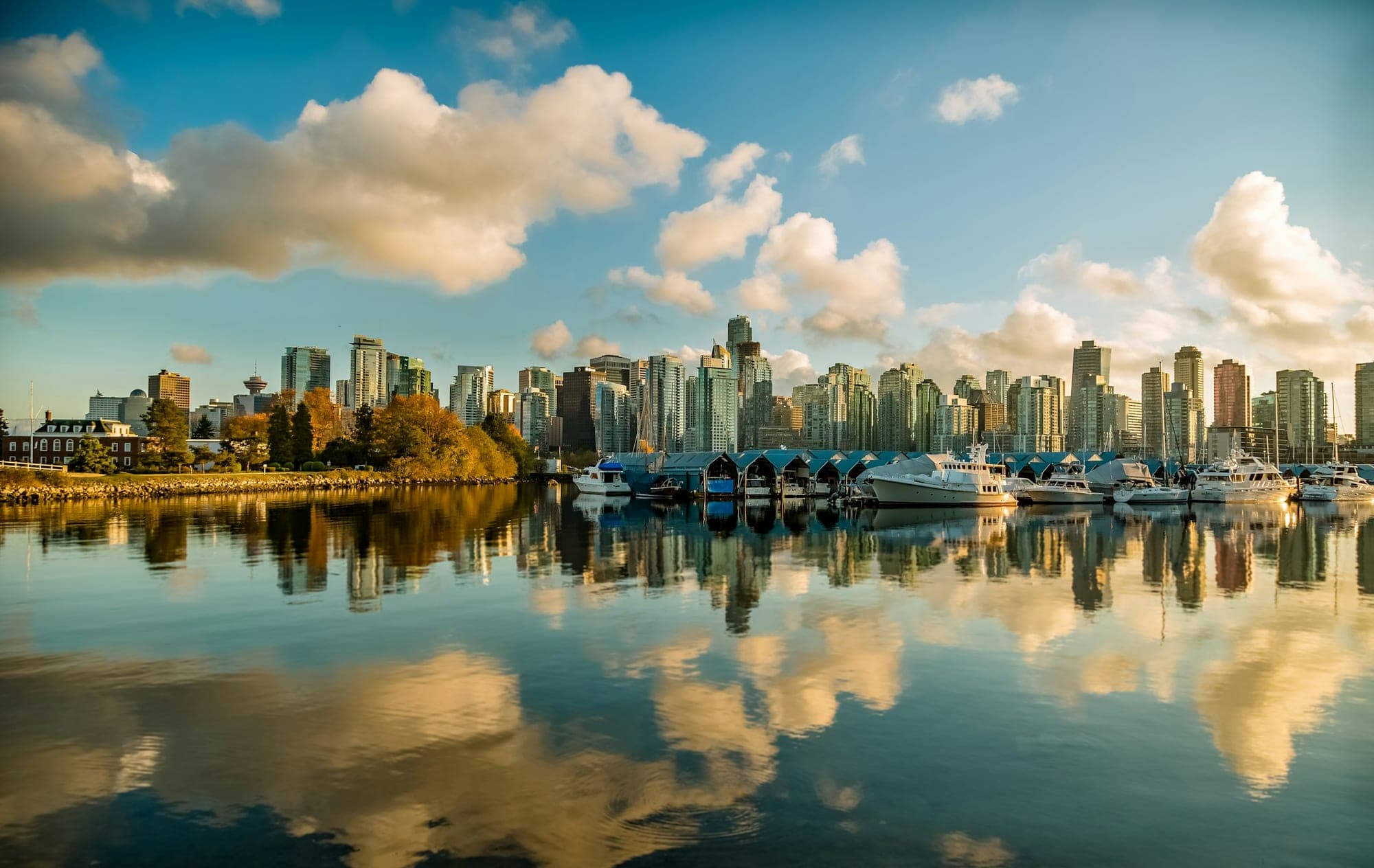 Downtown Vancouver skyline at dusk with Coal Harbour in the foreground and the North Shore mountains behind the glass towers.